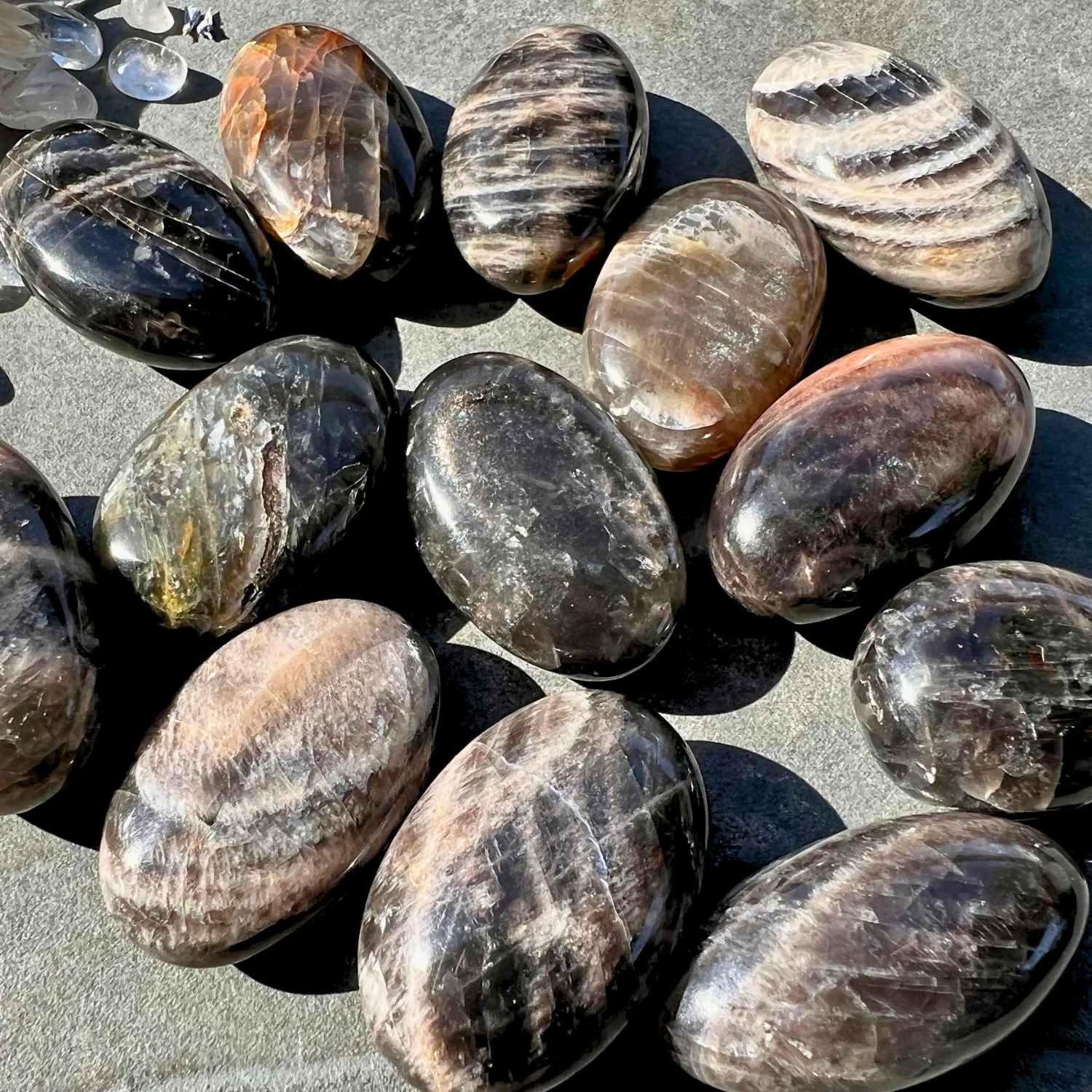 Schwarze Mondstein Handschmeichler im Sonnenlicht mit Regenbogen Reflexen