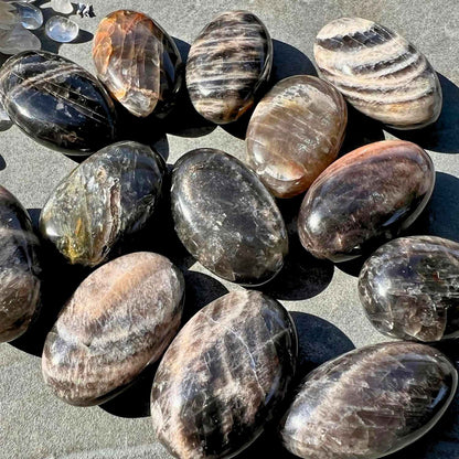 Schwarze Mondstein Handschmeichler im Sonnenlicht mit Regenbogen Reflexen