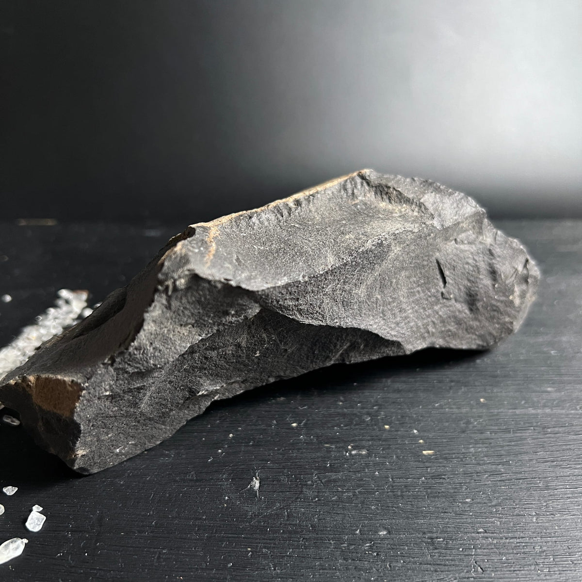 Roher grauschwarzer Stein mit schroffen Bruchkanten und ockerfarbenen Adern, längliche Form | Happy Minerals