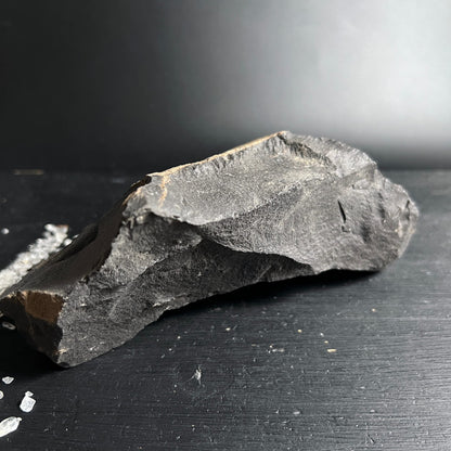 Roher grauschwarzer Stein mit schroffen Bruchkanten und ockerfarbenen Adern, längliche Form | Happy Minerals