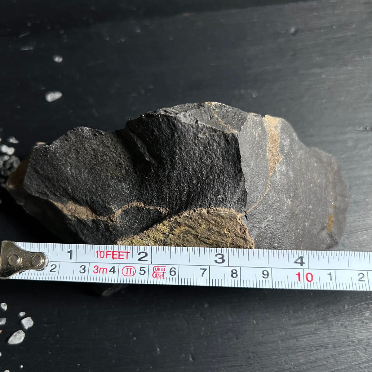 Roher schwarzer Onyx Stein mit rauer Bruchkante, grauen Zonen und gelblich-olivfarbenen Adern | Happy Minerals