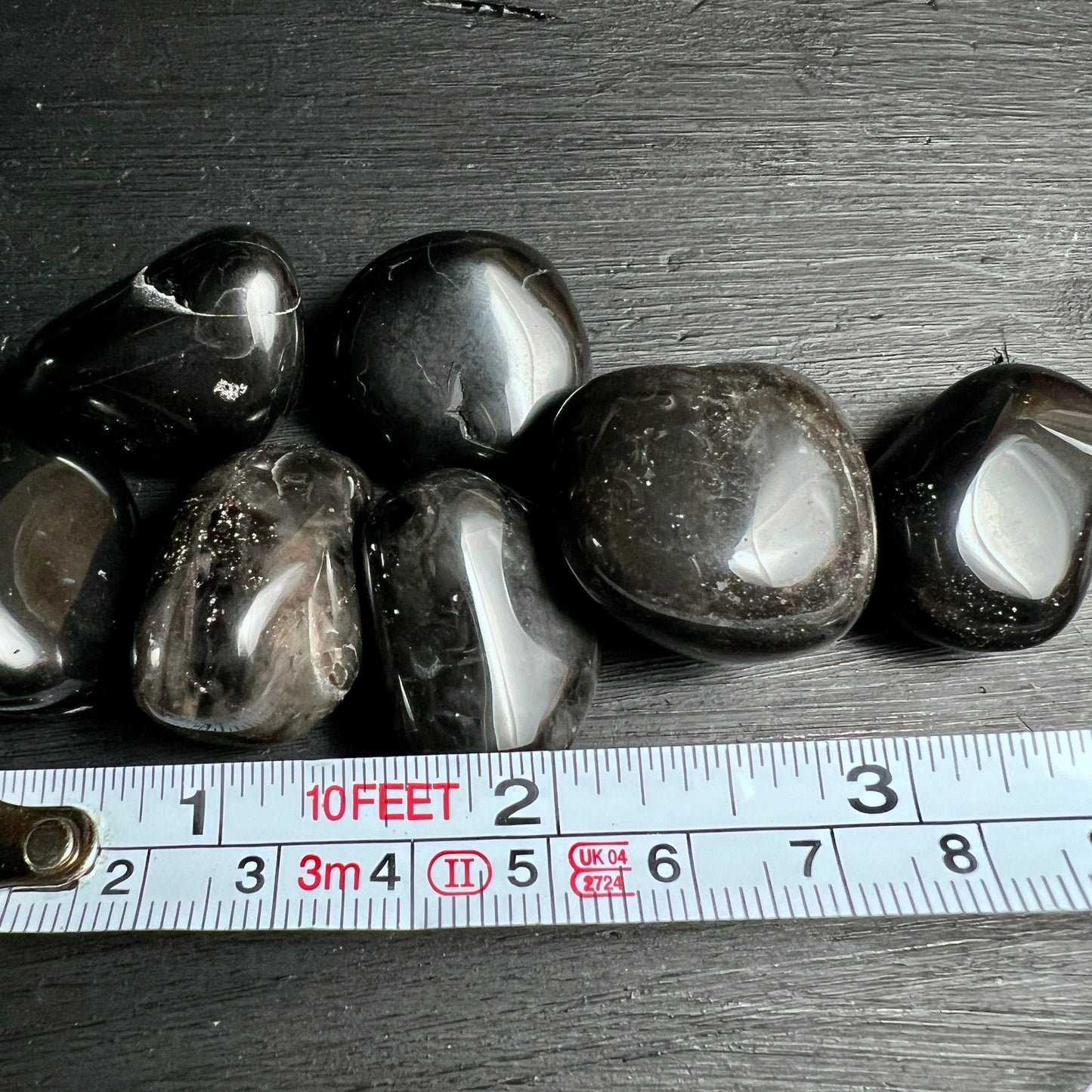 Schwarzer Onyx Trommelsteine | Brasilien | Maßband | Größenmessung | Happy Minerals Sortiment