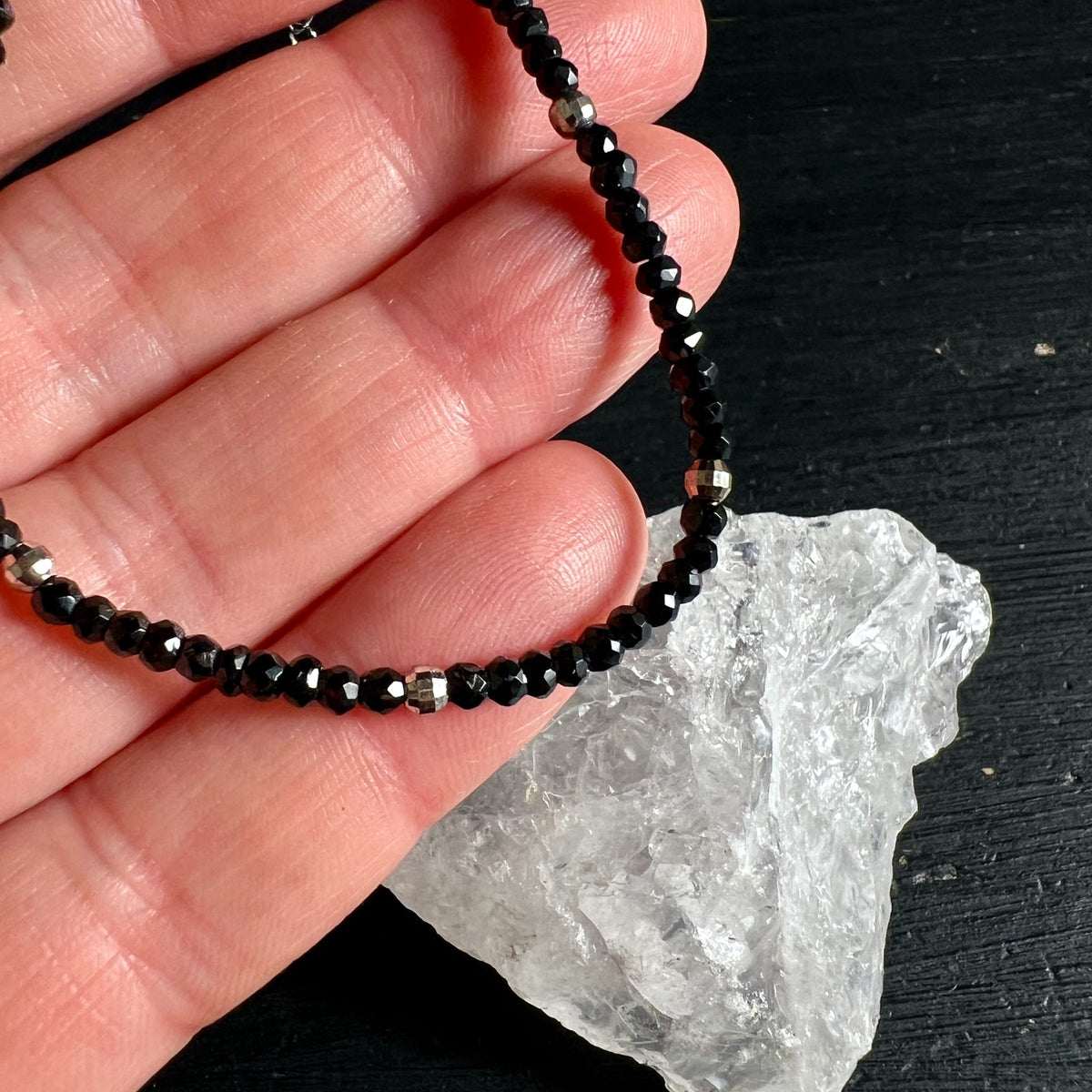 Schwarzes Spinell Armband mit facettierten Perlen und silbernen Pyrit-Akzenten, auf Hand gehalten | Happy Minerals