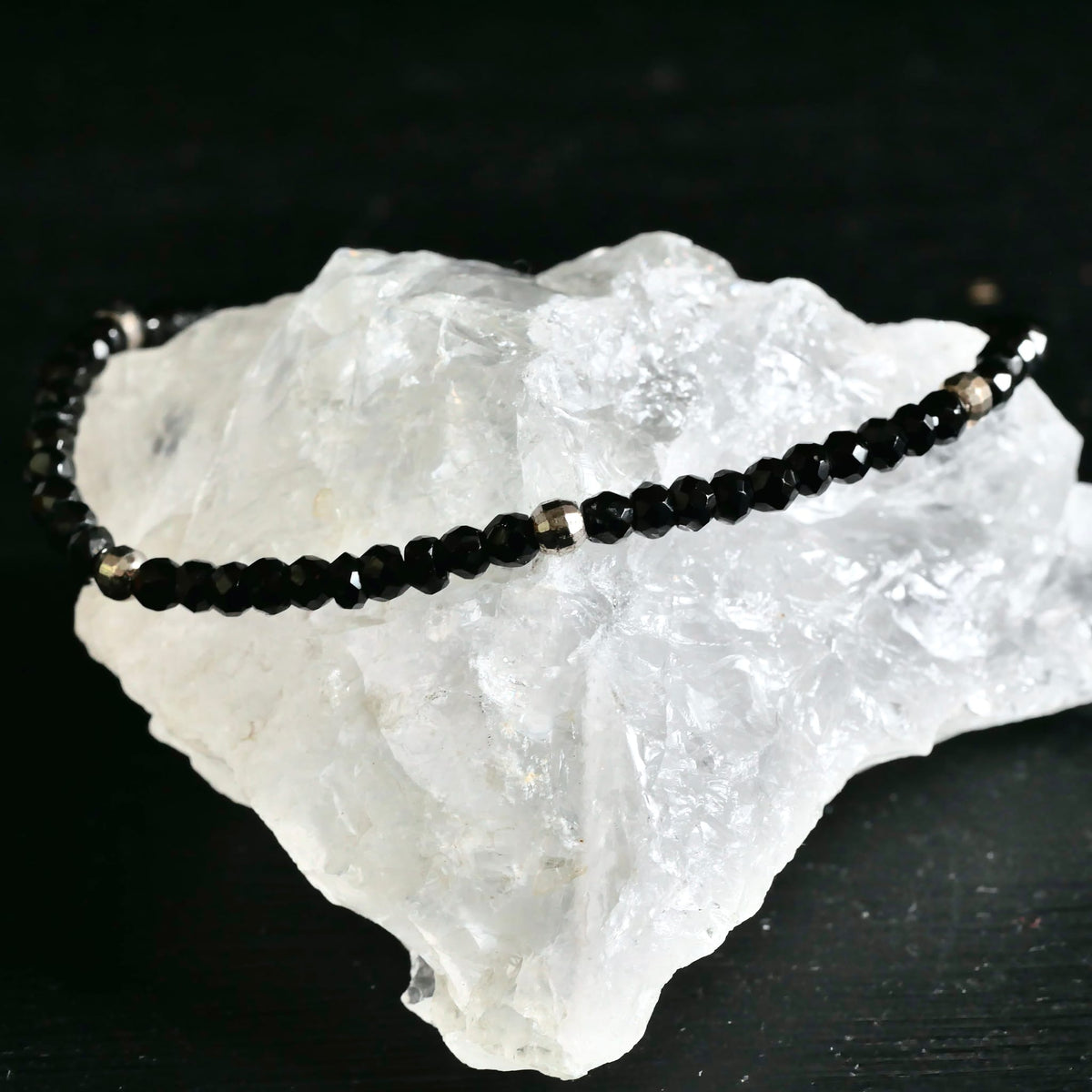 Nahaufnahme facettierte Spinell Kugeln auf weißem Bergkristall | glänzend schwarz-silber | Happy Minerals