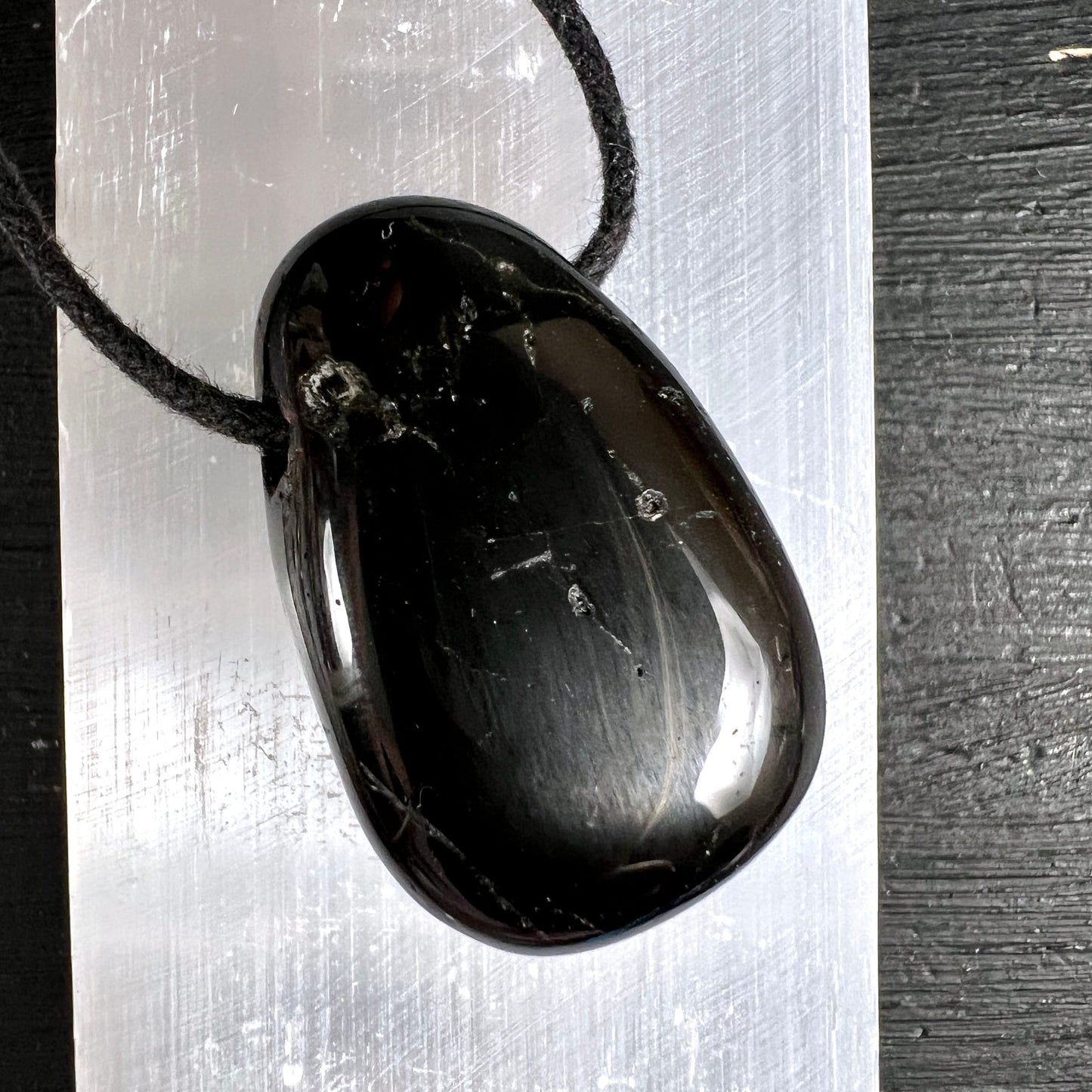 Schwarzer Turmalin Anhänger, oval poliert, tiefschwarz mit silbrigen Streifen und Glanzlichtern, schwarze Kordel | Happy Minerals