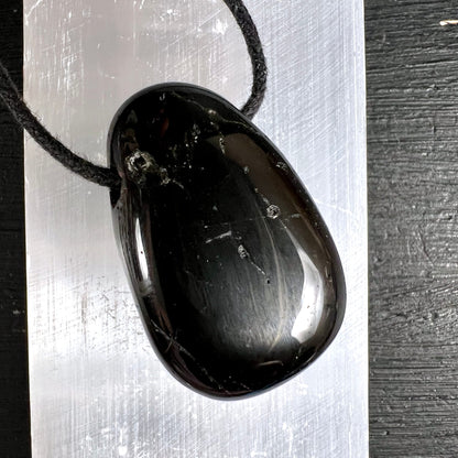 Schwarzer Turmalin Anhänger, oval poliert, tiefschwarz mit silbrigen Streifen und Glanzlichtern, schwarze Kordel | Happy Minerals