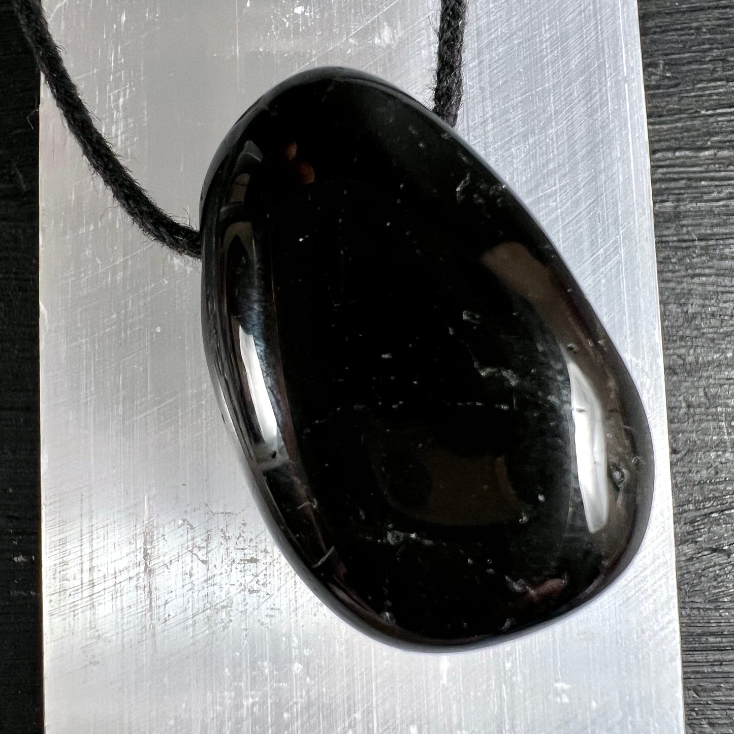 Schwarzer Turmalin Anhänger, oval poliert, tiefschwarz mit silbrigem Glanz, weisse Mineraleinschlüsse, schwarze Kordel | Happy Minerals