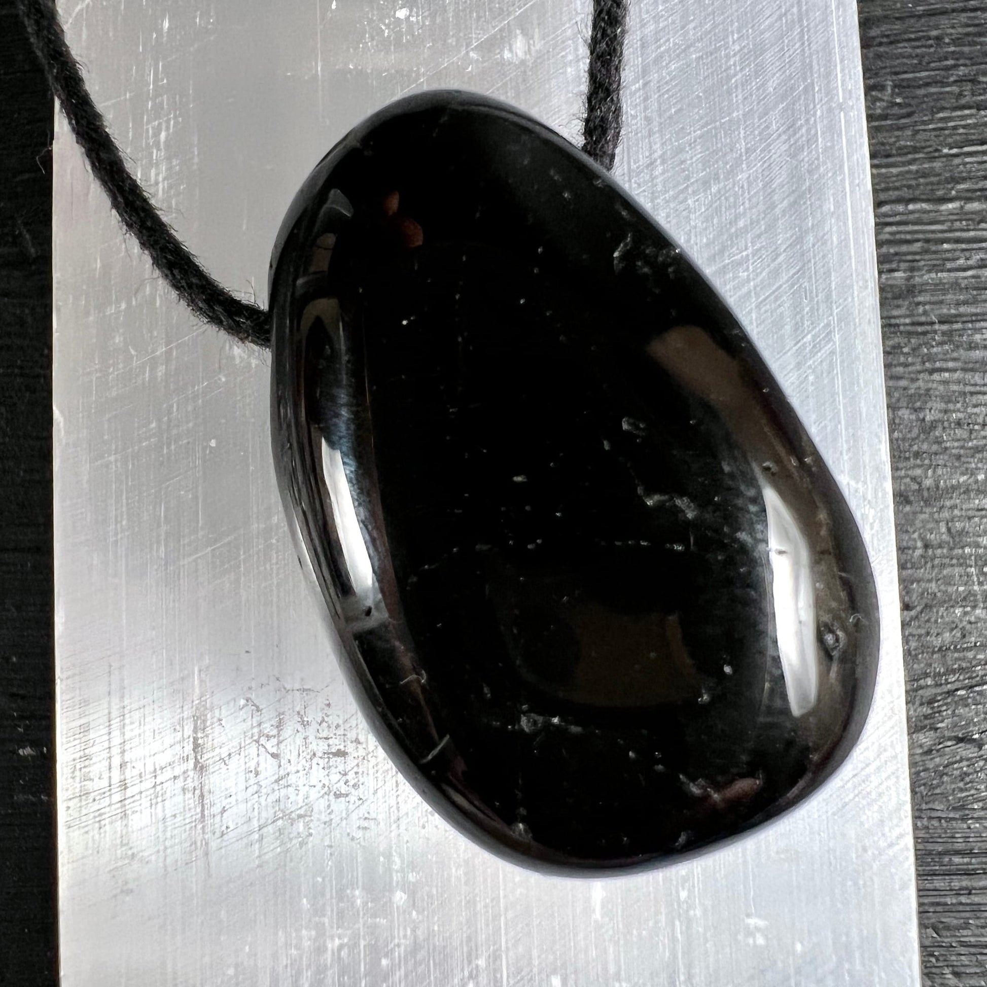 Schwarzer Turmalin Anhänger, oval poliert, tiefschwarz mit silbrigem Glanz, weisse Mineraleinschlüsse, schwarze Kordel | Happy Minerals