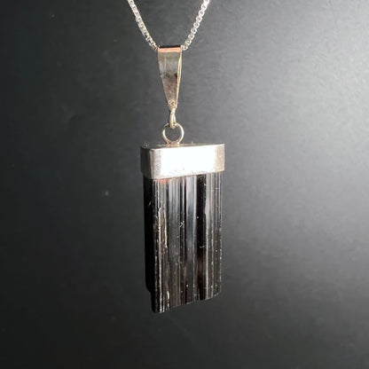 Schwarzer Turmalin Anhänger | seitliche Ansicht | markante Silberkappe | tiefschwarze Streifen | Happy Minerals