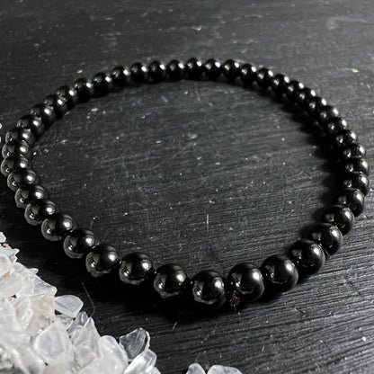 Schwarzer Turmalin Armband, hochglanzpolierte tiefschwarze Kugelperlen 3-4mm, groessere Perlen vorne, elastisch | Happy Minerals