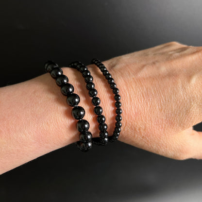 Drei schwarze Turmalin Perlenarmbänder am Handgelenk, tiefschwarz glänzend, runde Perlen in 3 Größen gestaffelt | Happy Minerals