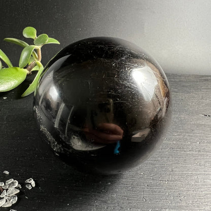 Schwarzer Turmalin Kugel 73mm, tiefschwarz-glänzend mit feinen silbrigen Kratzern, spiegelnde Oberfläche | Happy Minerals