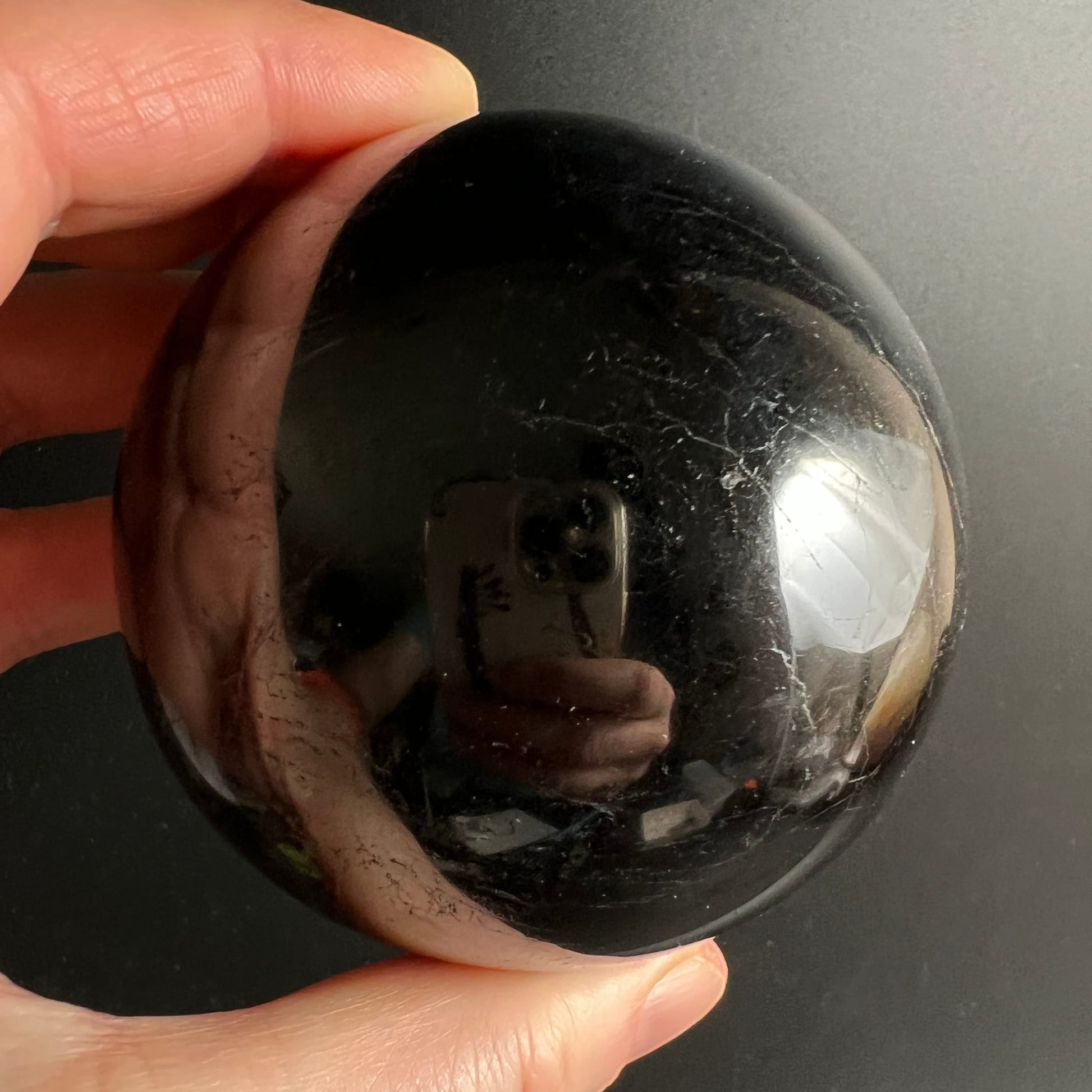 Schwarzer Turmalin Kugel 73mm, tiefschwarz glänzend mit silbrigen Ritzlinien, spiegelnde Oberfläche | Happy Minerals