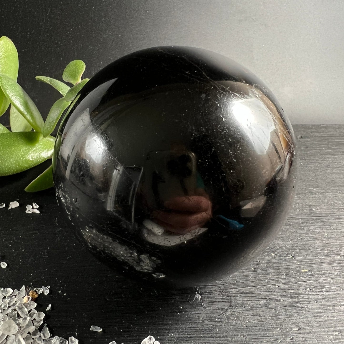 Schwarzer Turmalin Kugel 73mm, tiefschwarz glänzend mit feinen Kratzspuren, spiegelt Umgebung | Happy Minerals