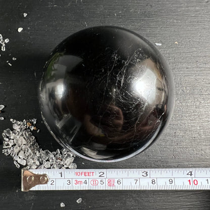 Schwarzer Turmalin Kugel von oben | Maßband zeigt ca. 9cm | weiße Äderung | Madagaskar | Happy Minerals