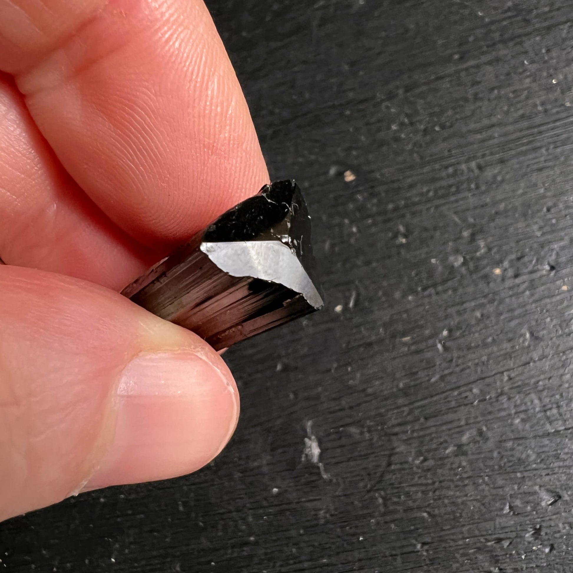 Schwarzer Turmalin Rohkristall | Nahaufnahme in Fingern | changierende Streifenstruktur | Happy Minerals Unikat