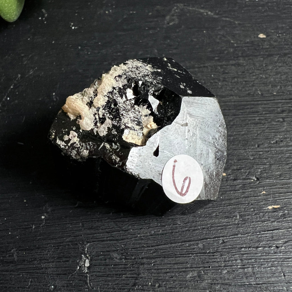 Schwarzer Turmalin roh, tiefschwarz glänzend mit weiss-beigen Feldspat-Einschlüssen, rechts silbergrauer Glimmerbelag | Happy Minerals