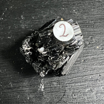 Schwarzer Turmalin roh, tiefschwarz mit vertikalen Riefen, metallischem Glanz und weißen Mineraleinschlüssen | Happy Minerals
