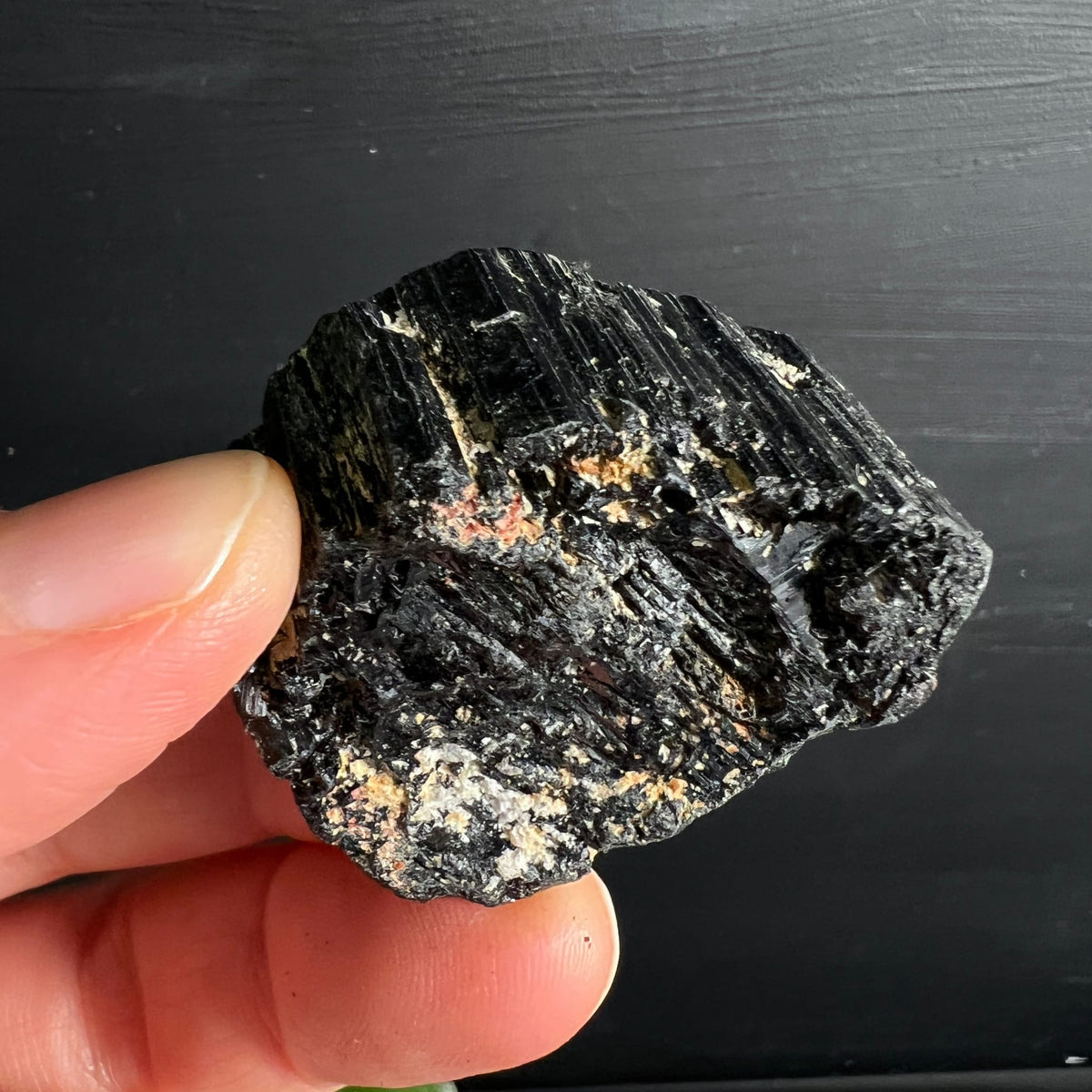 Schwarzer Turmalin roh, tiefschwarz mit vertikalen Rippen, weiss-beigen Einschlüssen und rosa Flecken | Happy Minerals
