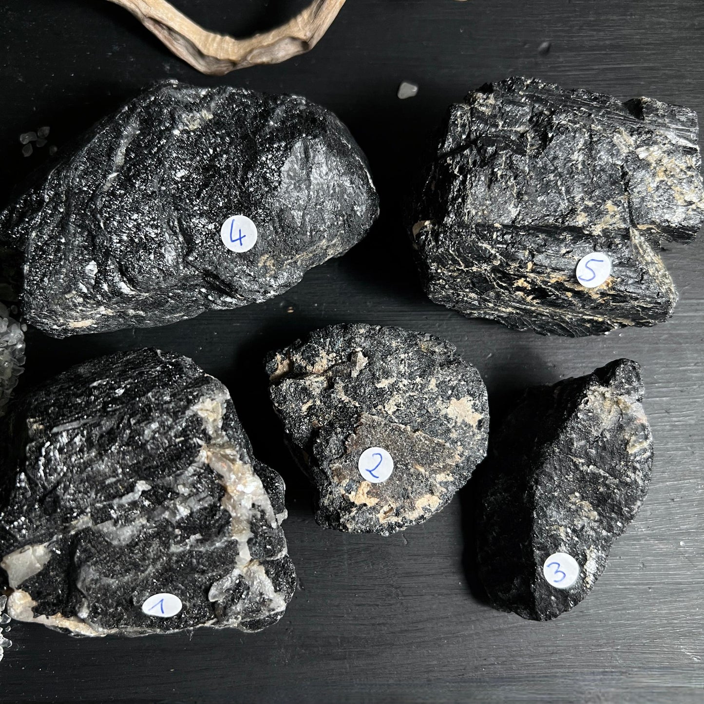Fünf schwarze Turmalin Rohsteine aus Brasilien mit Quarz auf dunklem Untergrund