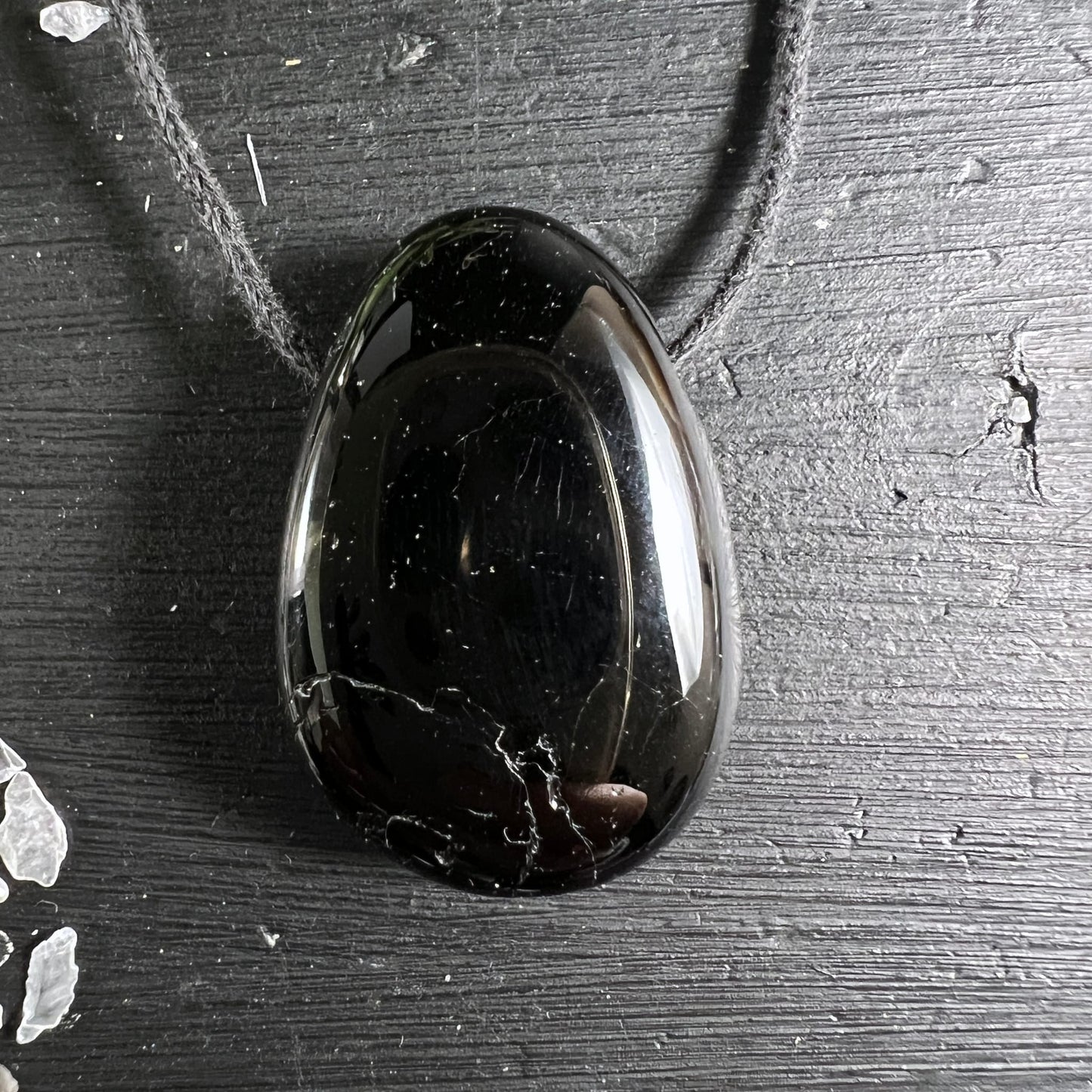 Schwarzer Turmalin Tropfen | glänzend | auf dunklem Holz | grauer Schnur | Madagaskar | Happy Minerals