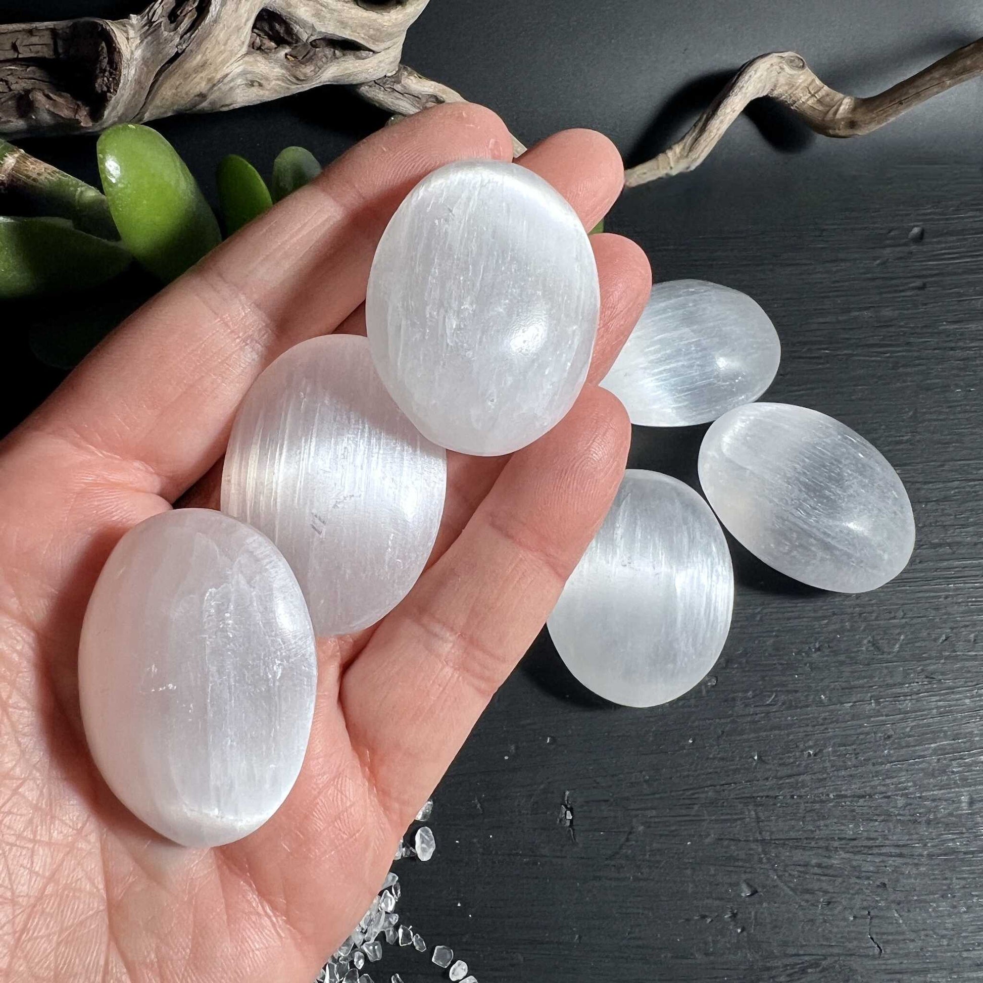 Seidig schimmernde Selenit Handschmeichler wie Mondlicht auf dunklem Holz | Happy Minerals 