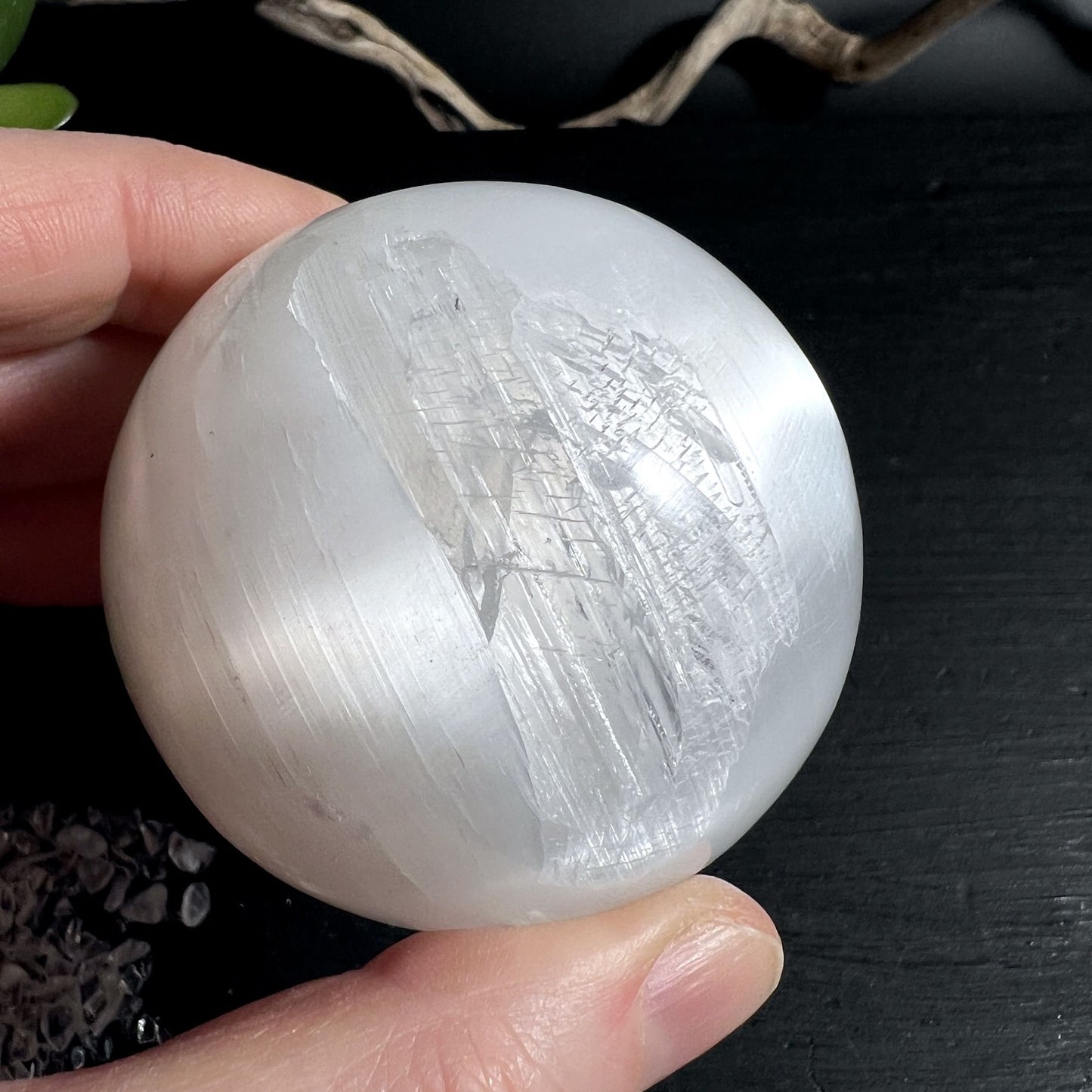 Selenitkugel in der Hand gehalten zeigt perfekte Größe für Meditation und Energiearbeit