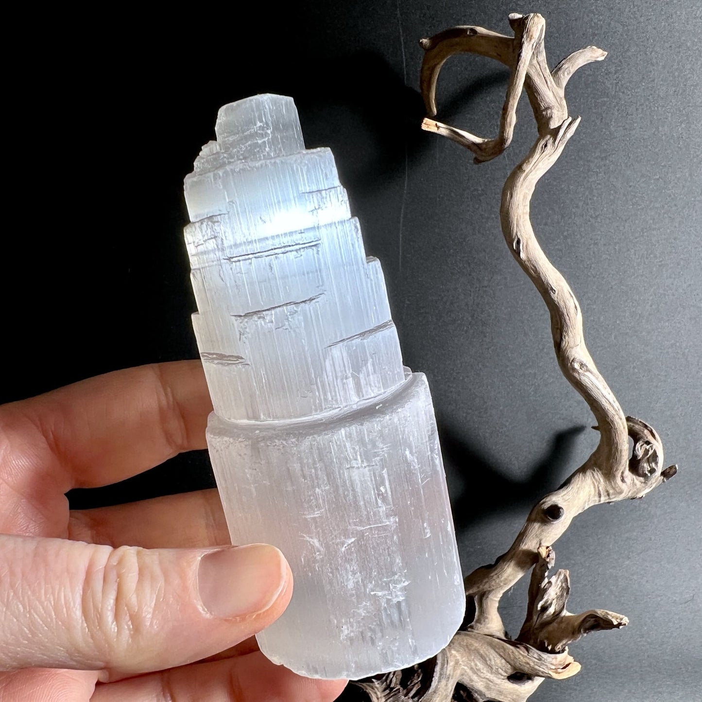 Selenitturm in der Hand gehalten transluzent weiß mit Lichtreflexen Mondlicht