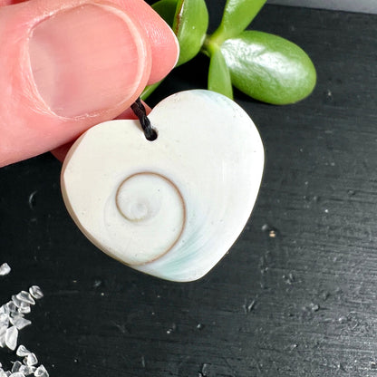 Shiva Auge Herzanhänger | Hand haltend | Bohrloch Detail | cremeweiß Spirale | Bali | Happy Minerals