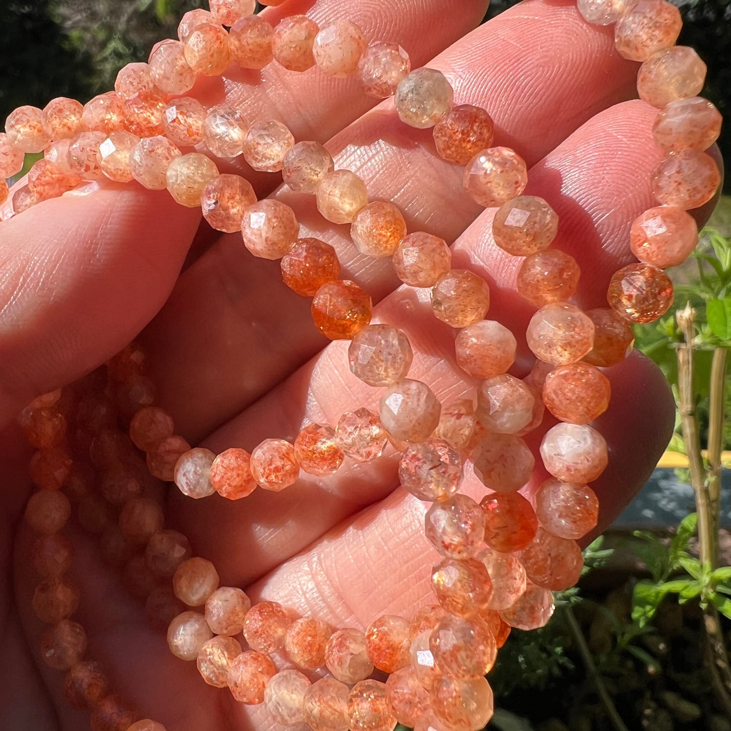 Sonnenstein Tansania | 4mm facettiert | Strang in der Hand | Sonnenlicht | transparentes Pfirsichorange | Happy Minerals