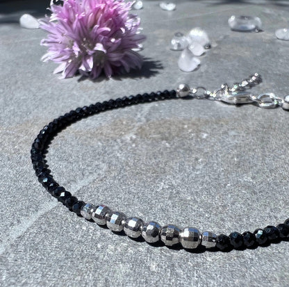 Schwarzes | Spinell-Armband | silberne Akzentperlen | neben lila Blüte | und Kristallen | Happy Minerals
