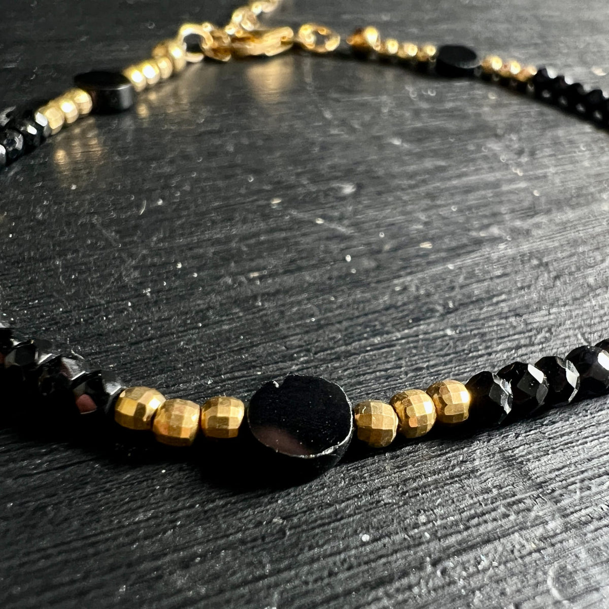 Spinell | Nahaufnahme | goldene Akzente | schwarze Facetten | Detail | Happy Minerals
