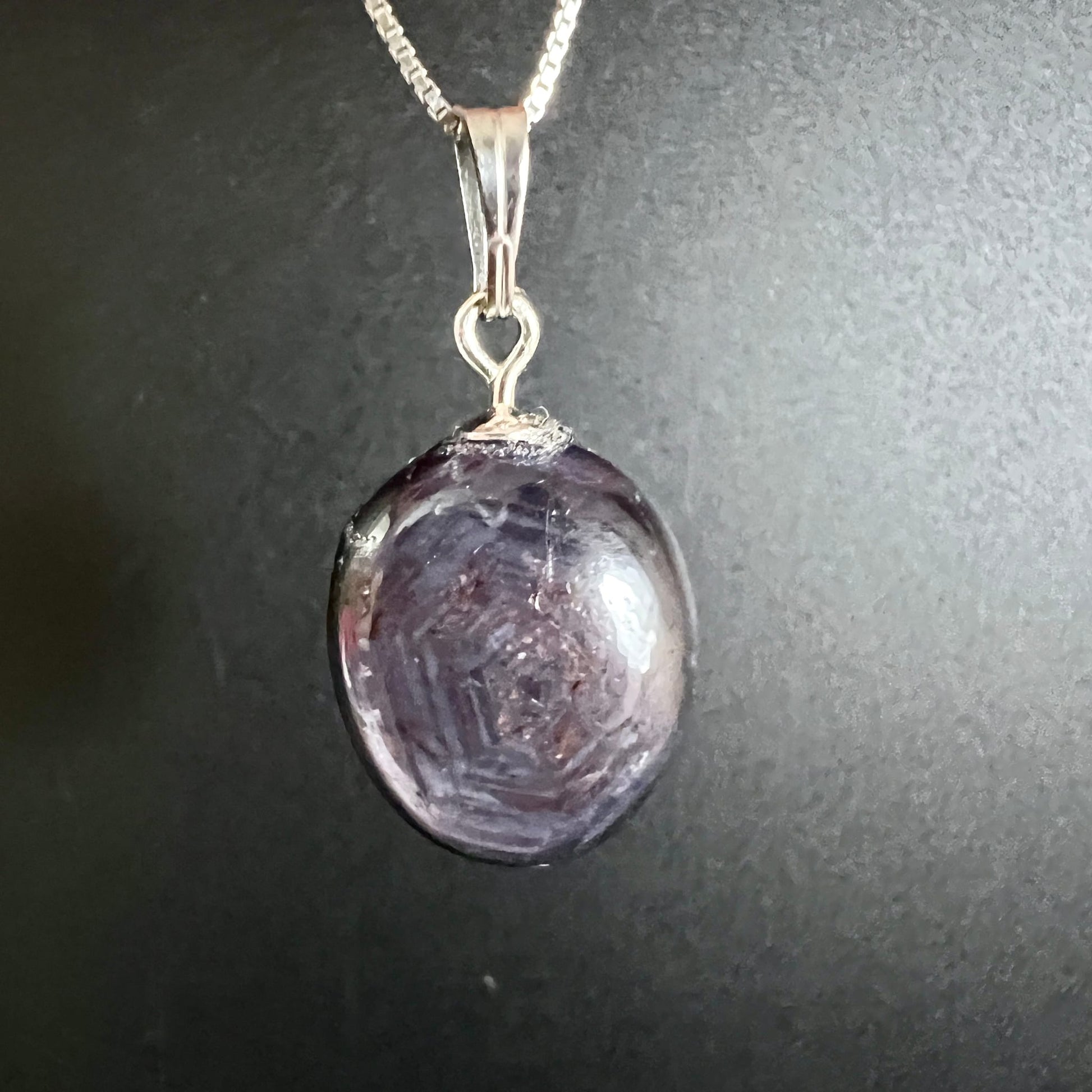 Sternrubin Cabochon oval, violett-lila mit konzentrischen Wachstumszonen und sichtbarem Asterismus-Stern, Silberöse | Happy Minerals