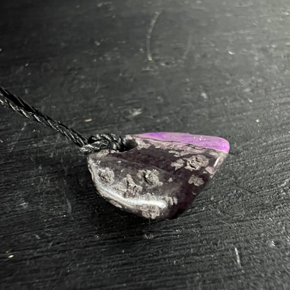 Sugilith Anhaenger, dunkles Violett-Grau mit rosa Zone, raue Textur, an schwarzer Kordel | Happy Minerals