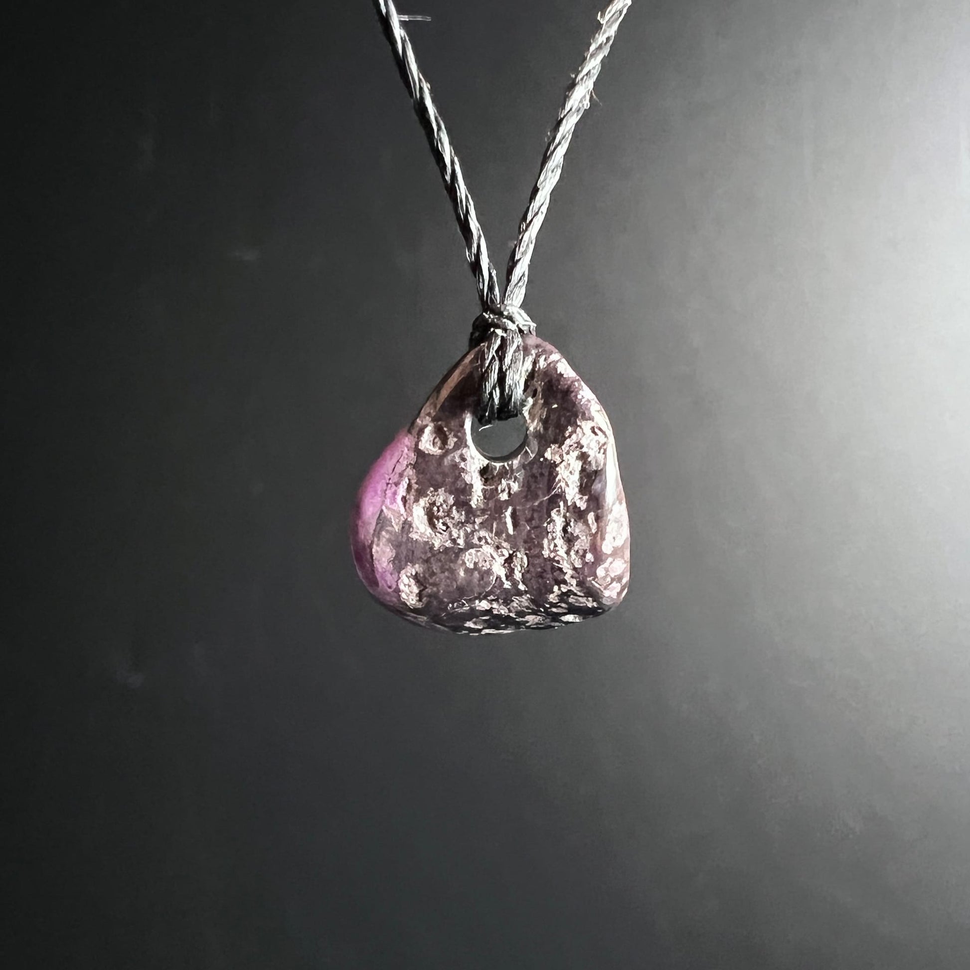 Sugilith Anhaenger, dreieckige Form, dunkles Violett mit rosa Zone und weissen Einschluessen, an Kordel | Happy Minerals