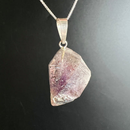 Roher Kristallanhaenger, transparent-rosa mit violetten Wolken und feinen rotbraunen Nadeleinschluessen, Silberoese | Happy Minerals
