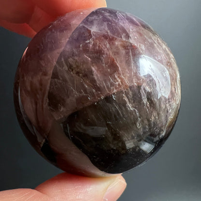 Super Seven Kugel in Hand | Nahaufnahme | rosa-braune Streifen | Happy Minerals | Melody Stone Unikat