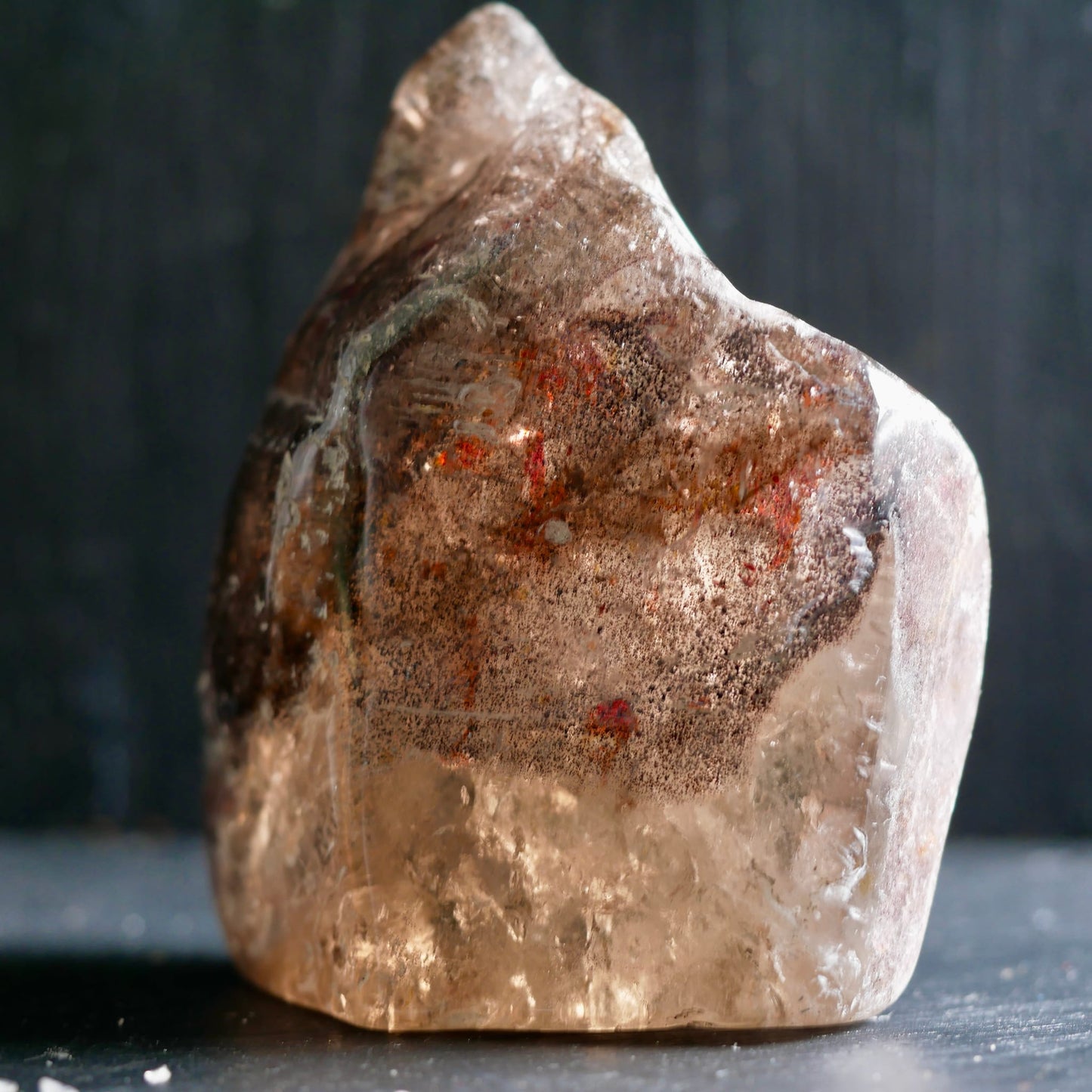 Super Seven Melody Stone | stehend auf Tisch | rote Flecken | klare Kristallstruktur | Happy Minerals