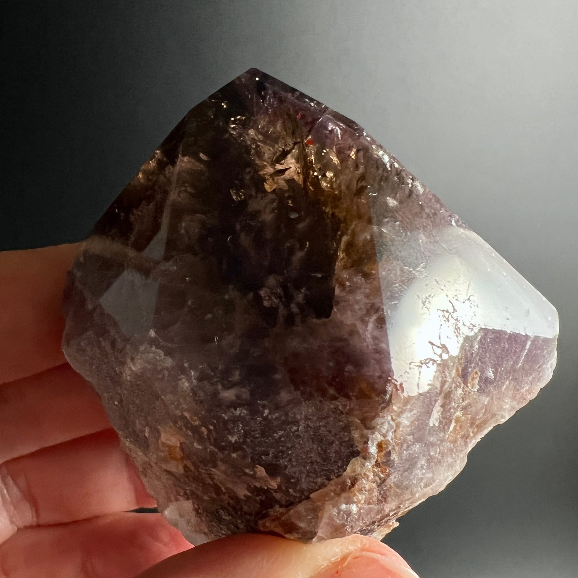 Super Seven Melody Stone | Variante C | Nahaufnahme Hand | dunkel violett | klare Spitze | leuchtend | Happy Minerals