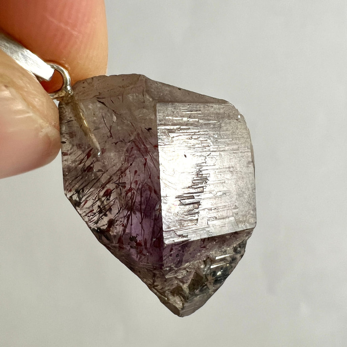 Roher Kristallanhänger mit dunkelvioletten und rauchgrauen Zonen, schwarzen Nadeleinschlüssen, facettierte Kante | Happy Minerals
