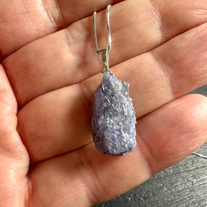 Tansanit Rohstein | tiefdunkles Blauviolett | auf Handfläche | 925 Silberkette | Größenvergleich | Happy Minerals