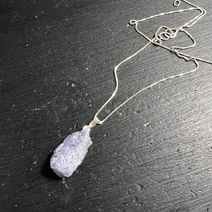 Tansanit Rohstein | blau-violett | 925 Silberkette | liegend auf schwarzem Holz | Unikat | Happy Minerals