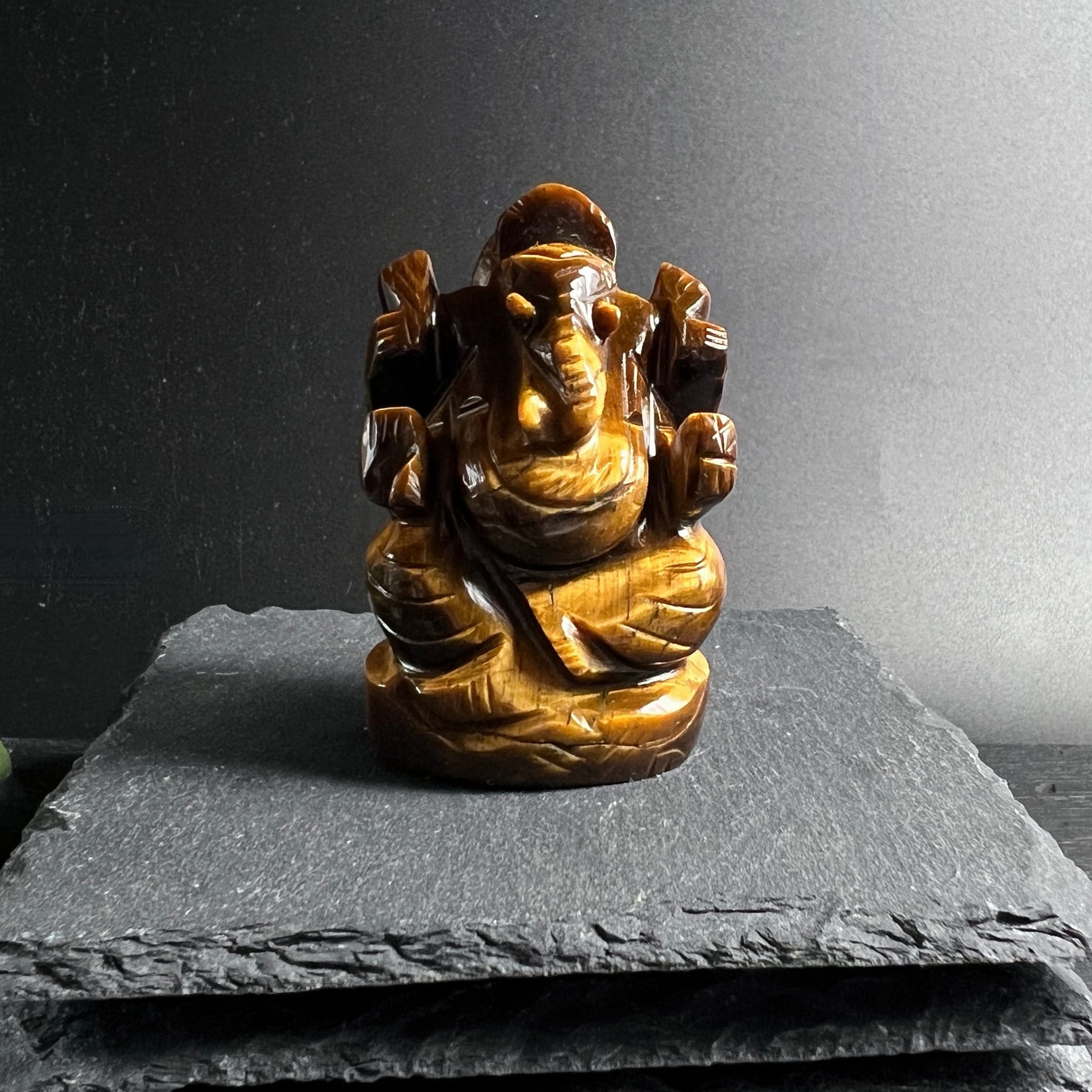Tigerauge Ganesha | Frontalansicht | auf Schieferplatte | symmetrische Pose | golden | Happy Minerals