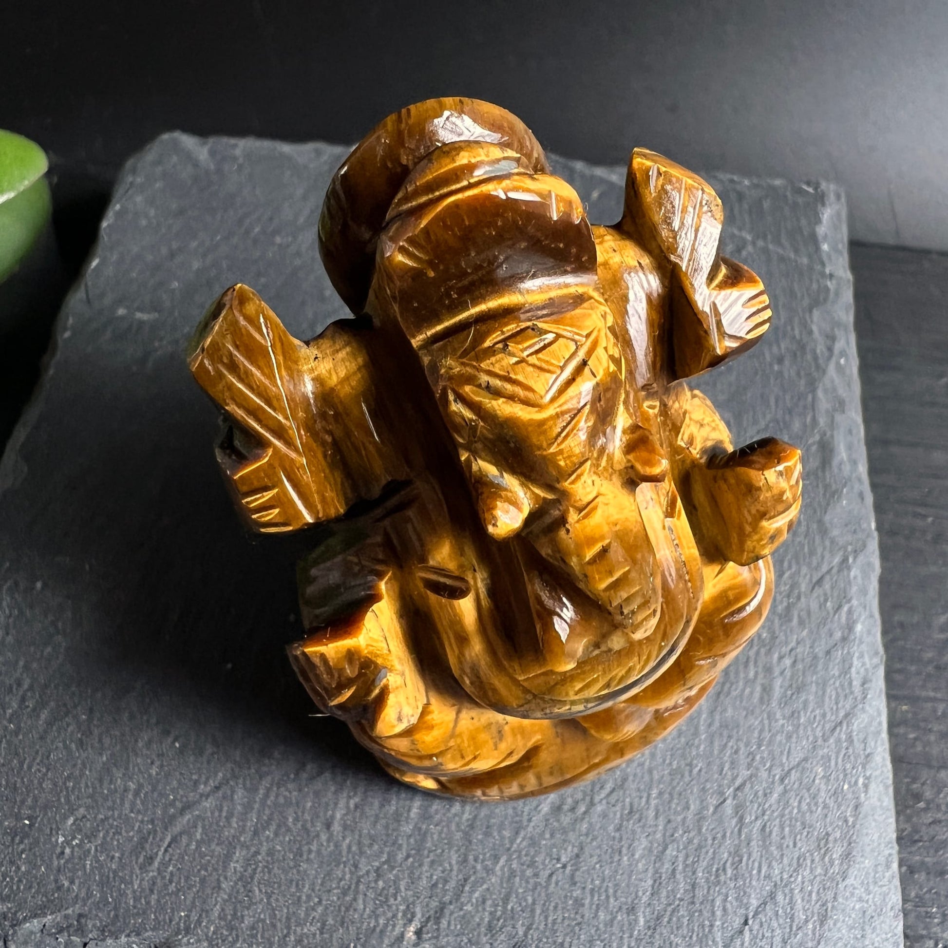 Tigerauge Ganesha | Vogelperspektive | vier Arme | warmes Goldbraun | Schieferplatte | Happy Minerals